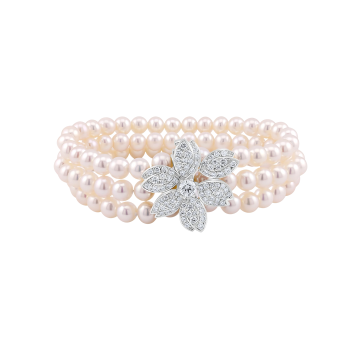 Pearl bracelet with a diamond flower clasp on a white background