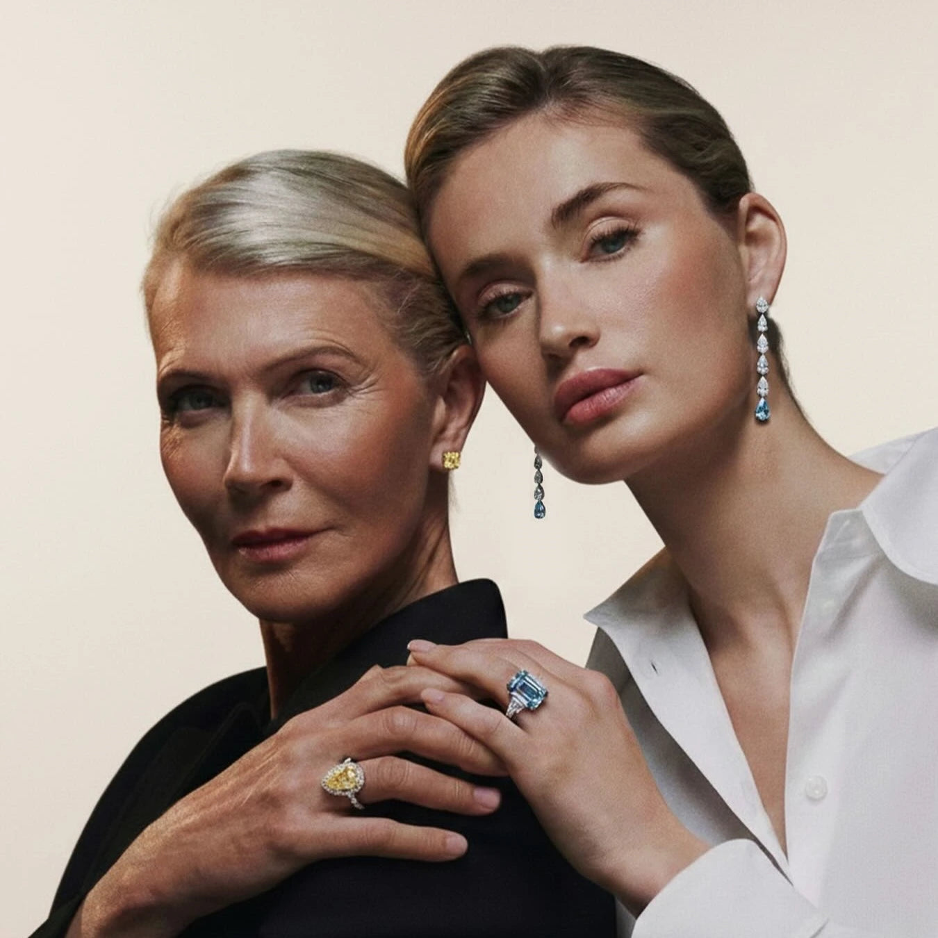 Two women wearing jewelry, including rings and earrings, against a neutral background.