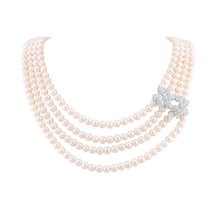Three-strand pearl necklace with a diamond brooch on a white background